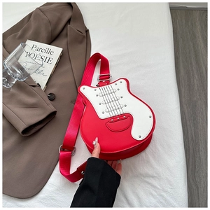 Detailed view of red guitar shaped crossbody bag with wide strap on white fabric