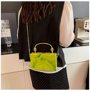Detail of neon green marble acrylic clutch bag with gold handle and chain on model