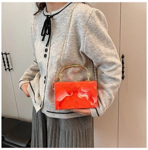 Detail of orange marble acrylic clutch bag with golden vintage handle and chain strap