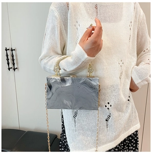Detail of grey marble pattern acrylic clutch with gold round handle and chain strap