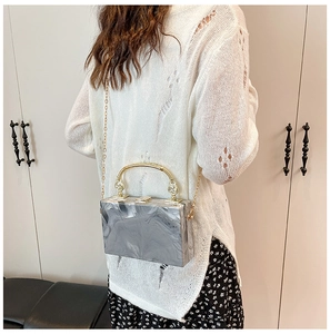Detail of gray marble pattern acrylic clutch with gold circular handle and chain
