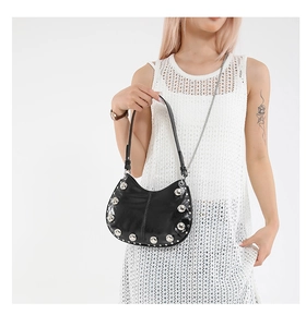 Close-up of black leather crescent bag with silver studs and a metallic chain strap