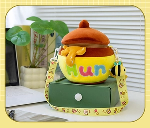 Detail of cute honey jar plush bag with Hun embroidery and bee charm on a desk