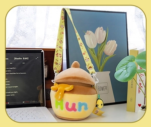 Detail of honey pot plush bag featuring Hun embroidery and cute bee zipper charm