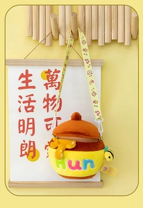 Detail view of plush honey pot crossbody bag with bee pendant on a wooden hanger