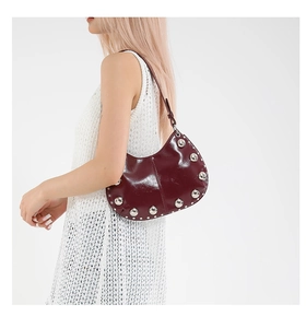 Détail du sac croissant rouge vin avec rivets métalliques argentés sur cuir brillant