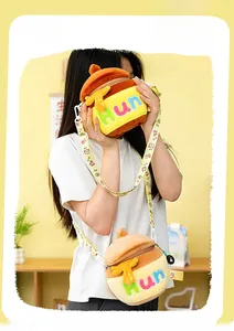 Detailed close-up of plush honey pot crossbody bag with embroidered lettering and strap