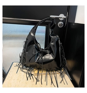 Gros plan détaillé d'un sac hobo noir brillant à franges avec un nœud élégant