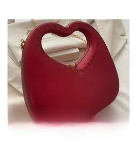 Close-up of red heart acrylic evening bag with gold chain and circular dot handle details