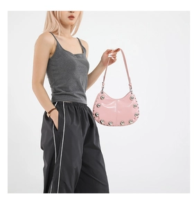 Close-up of pink patent leather moon bag with silver studs and adjustable strap