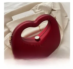 Red heart-shaped acrylic evening bag with hollow handle and gold chain detail