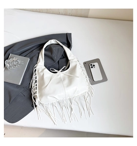 Détail du sac hobo blanc avec franges et nœud dans un décor de style de vie moderne