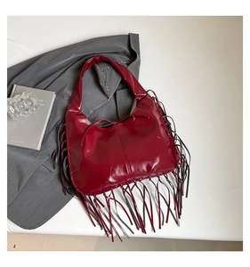 Gros plan du sac fourre-tout croissant rouge foncé avec de longues franges et un nœud