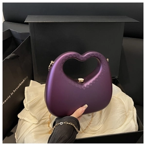 Detail of deep purple heart-shaped acrylic handbag with gold metal chain and matte finish
