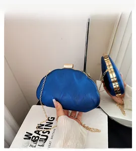 Detail of royal blue clutch with shell texture, gold frame, and metal chain strap