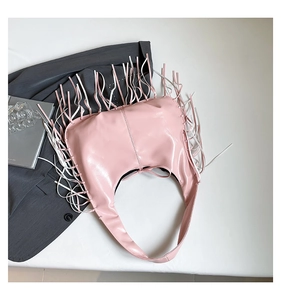 Détails de franges roses et blanches sur un sac cabas en cuir PU brillant dans un décor mode