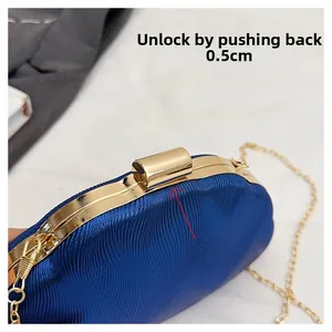 Detail of blue shell clutch featuring gold lock mechanism and wave texture pattern