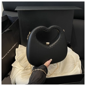 Detailed view of black heart-shaped handbag with gold chain in a premium gift box