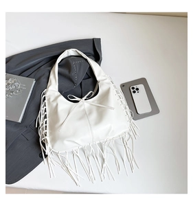 Détail du sac hobo en cuir PU blanc avec de longues franges et nœud sur fond blanc
