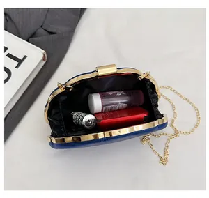 Macro shot of blue textured clutch interior showing capacity for cosmetics and gold chain
