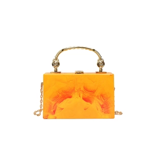 Acrylic clutch bag with orange marble pattern and golden metal handle in 100 chars