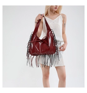 Détail du sac croissant bordeaux avec de longues franges et une finition brillante