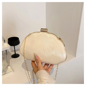 Detail of pearlescent shell clutch bag featuring wave texture and golden chain strap