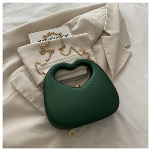 Detail of dark green heart bag with matte finish and chunky gold chain strap