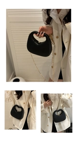 Detail of black heart-shaped evening bag with cutout handle and gold chain strap
