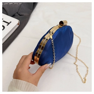 Detail of dark blue satin evening clutch with gold metal frame and detachable chain strap