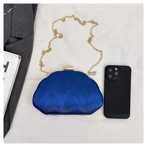 Detail of navy blue evening clutch featuring wavy texture and golden metal chain strap