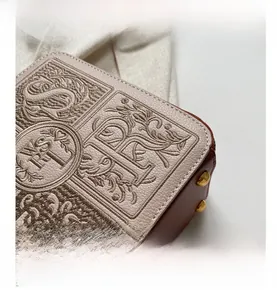 Detailed close-up of retro letter embroidery and litchi texture on beige crossbody box bag