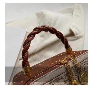 Detail of woven brown handle with gold rivets and camellia flower zipper on handbag