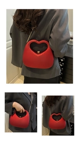 Detail of red heart-shaped hard shell handbag with gold chain strap and relief dots