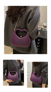 Detailed view of purple heart-shaped handbag with cutout handle and gold chain strap