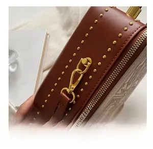 Detail of brown leather handbag featuring gold rivets and detachable metal hook