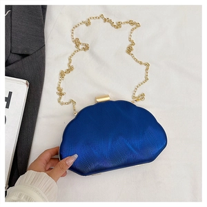 Detail of royal blue shell-shaped evening clutch with ripple texture and gold chain strap