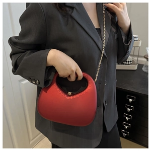 Close-up of wine red matte heart handbag with textured handle and gold chain strap