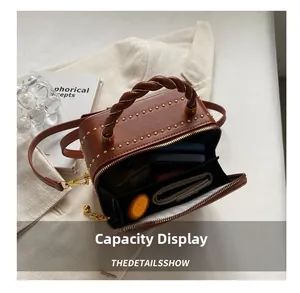 Brown rivet box bag with twisted handle showing interior capacity for phone and wallet