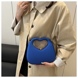 Detail of blue heart-shaped handbag with dot-textured handle and gold chain strap