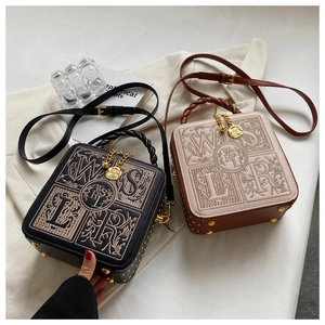 Detail of embroidered small square bags with floral patterns and gold rivets