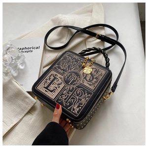 Close-up of black box bag showing intricate floral embroidery and gold metal hardware