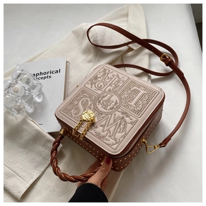 Detail of square box bag with intricate embroidery, gold studs and floral chain charm