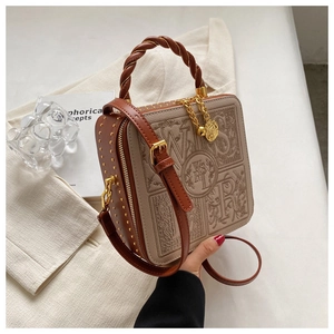Close-up of vintage box bag with letter embossing, woven handle, and gold rivet details