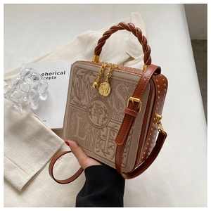 Close-up of beige crossbody bag featuring braided handle and gold flower charm detail