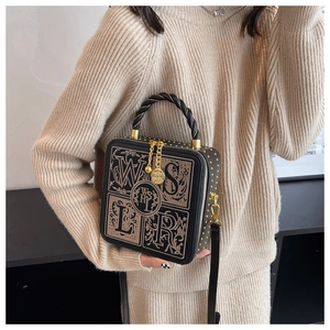 Detail of embroidered box bag with camellia zipper pull and twisted rope handle