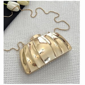 Detailed close-up of golden shell-shaped evening clutch bag with glossy metallic finish