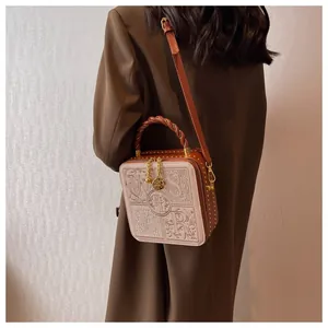 Detail of vintage brown box bag featuring intricate embossed letters and braided handle