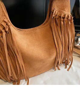 Detail of soft matte suede material and long fringe tassels on a brown hobo bag