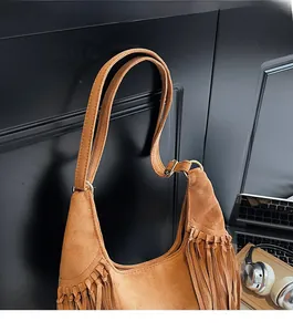 Close-up of brown suede hobo bag with long fringe details and golden metal hardware